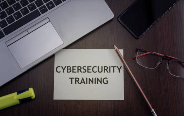 Top view of laptop, phone, glasses and pencil with card with inscription cybersecurity training.